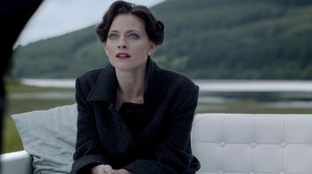 Movie still from “Sherlock” (2010), created by Steven Moffat – A woman sitting on top of a white couch next to a body of water; Close Up shot, Over the shoulder angle