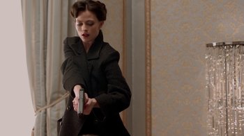 Movie still from “Sherlock” (2010), created by Steven Moffat – A woman in a black coat holding a cell phone; Medium shot, Over the shoulder angle