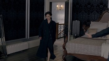 Movie still from “Sherlock” (2010), created by Steven Moffat – A woman in a black coat walking down a hallway; Wide shot, High angle