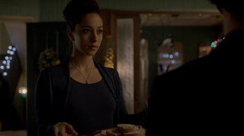 Movie still from “Sherlock” (2010), created by Steven Moffat – A woman standing in a kitchen holding a plate of food; Medium shot, Over the shoulder angle