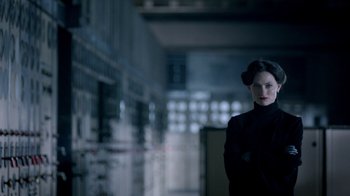 Movie still from “Sherlock” (2010), created by Steven Moffat – A woman in a black outfit standing in a dark room; Close Up shot, Low angle