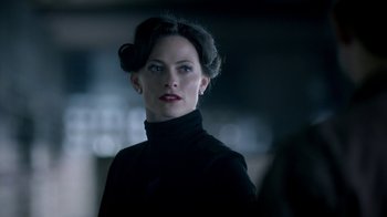 Movie still from “Sherlock” (2010), created by Steven Moffat – A woman in a black outfit looking to her left; Close Up shot, Over the shoulder angle