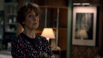 Movie still from “Sherlock” (2010), created by Steven Moffat – An older woman in a black and red floral shirt; Close Up shot, Over the shoulder angle