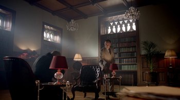 Movie still from “Sherlock” (2010), created by Steven Moffat – A man standing in a room next to a bookshelf; Wide shot, Low angle
