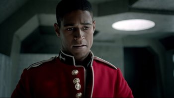 Movie still from “Sherlock” (2010), created by Steven Moffat – A man in a red and black uniform looking straight ahead; Close Up shot, Over the shoulder angle