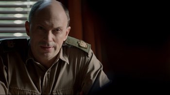 Movie still from “Sherlock” (2010), created by Steven Moffat – A man in a military uniform sitting in front of a curtain; Close Up shot, Over the shoulder angle