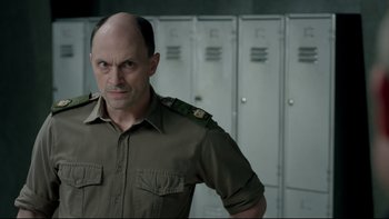 Movie still from “Sherlock” (2010), created by Steven Moffat – A man in a uniform standing in front of lockers; Close Up shot, Over the shoulder angle