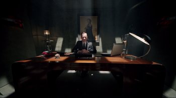 Movie still from “Sherlock” (2010), created by Steven Moffat – A man sitting at a desk in front of a laptop computer; Wide shot, Low angle