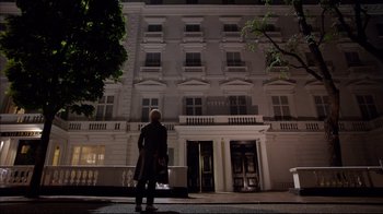 Movie still from “Sherlock” (2010), created by Steven Moffat – A person standing in front of a building at night; Wide shot, Low angle