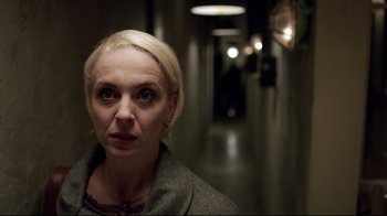 Movie still from “Sherlock” (2010), created by Steven Moffat – A woman standing in a dark hallway looking at the camera; Close Up shot, Over the shoulder angle