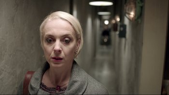 Movie still from “Sherlock” (2010), created by Steven Moffat – A woman in a gray coat standing in a hallway; Close Up shot, Over the shoulder angle