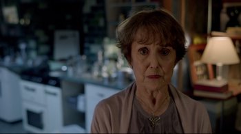 Movie still from “Sherlock” (2010), created by Steven Moffat – An older woman in a room with a table and chairs; Close Up shot, Over the shoulder angle