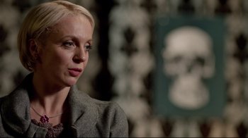 Movie still from “Sherlock” (2010), created by Steven Moffat – A woman with blonde hair wearing a gray jacket; Close Up shot, Over the shoulder angle