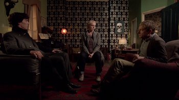 Movie still from “Sherlock” (2010), created by Steven Moffat – A group of people sitting in a living room; Wide shot, High angle