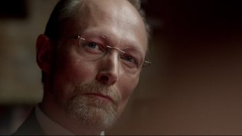 Movie still from “Sherlock” (2010), created by Steven Moffat – An older man with a goatee wearing glasses; Close Up shot, Low angle
