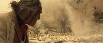 Movie still from “Spectre” (2015), directed by Sam Mendes – A man in a suit standing in the middle of a rubble pile; Wide shot, Over the shoulder angle