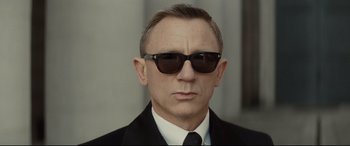 Movie still from “Spectre” (2015), directed by Sam Mendes – A person wearing a suit and sunglasses; Close Up shot, Low angle