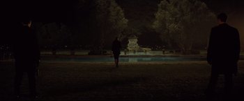 Movie still from “Spectre” (2015), directed by Sam Mendes – A person walking in a park at night near a fountain; Extreme Wide shot, Over the shoulder angle