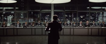 Movie still from “Spectre” (2015), directed by Sam Mendes – A man giving a speech in front of a group of people; Wide shot, Over the shoulder angle