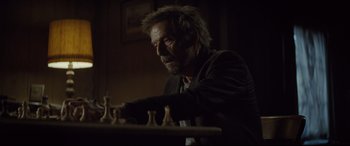 Movie still from “Spectre” (2015), directed by Sam Mendes – An older man playing a game of chess in a dark room; Close Up shot, Over the shoulder angle
