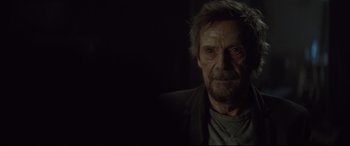 Movie still from “Spectre” (2015), directed by Sam Mendes – An old man with a beard and mustache is looking at the camera; Close Up shot, Over the shoulder angle