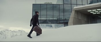 Movie still from “Spectre” (2015), directed by Sam Mendes – A person walking in the snow with a bag; Wide shot, Low angle