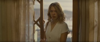 Movie still from “Spectre” (2015), directed by Sam Mendes – A woman standing in front of a window holding a wooden stick; Medium shot, Over the shoulder angle