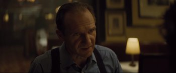 Movie still from “Spectre” (2015), directed by Sam Mendes – An older man wearing a blue shirt and black suspenders; Close Up shot, Over the shoulder angle