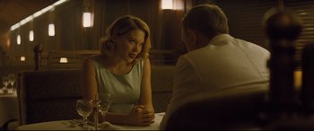 Movie still from “Spectre” (2015), directed by Sam Mendes – A woman sitting at a dinner table with a man; Medium shot, Over the shoulder angle