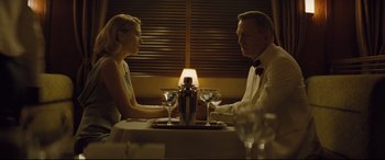 Movie still from “Spectre” (2015), directed by Sam Mendes – A man and a woman sitting at a dinner table; Medium shot, Over the shoulder angle