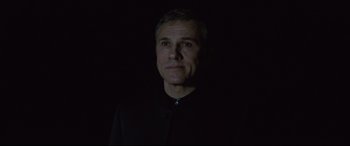 Movie still from “Spectre” (2015), directed by Sam Mendes – A man in a black shirt is in the dark; Close Up shot, Low angle
