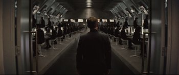 Movie still from “Spectre” (2015), directed by Sam Mendes – A man in a black suit standing in front of a group of people; Wide shot, High angle