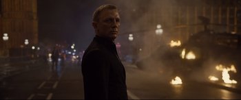 Movie still from “Spectre” (2015), directed by Sam Mendes – A man in a black suit standing in the street; Medium shot, Over the shoulder angle