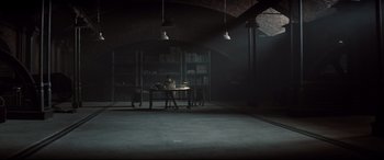 Movie still from “Spectre” (2015), directed by Sam Mendes – A person sitting at a table in a dark room; Extreme Wide shot, High angle