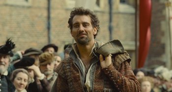 Movie still from “Elizabeth: The Golden Age” (2007), directed by Shekhar Kapur – A man with a beard is holding a purse; Medium shot, Over the shoulder angle