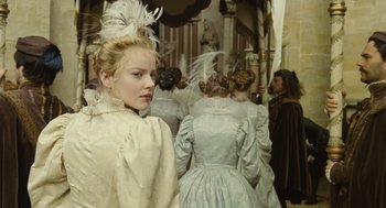 Movie still from “Elizabeth: The Golden Age” (2007), directed by Shekhar Kapur – A group of people in fancy dresses standing in a room; Medium shot, Over the shoulder angle