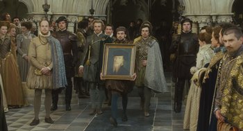 Movie still from “Elizabeth: The Golden Age” (2007), directed by Shekhar Kapur – A group of men in medieval garb carrying a framed portrait; Wide shot, Over the shoulder angle