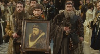 Movie still from “Elizabeth: The Golden Age” (2007), directed by Shekhar Kapur – A group of men holding up a picture of a bearded man; Close Up shot, Over the shoulder angle
