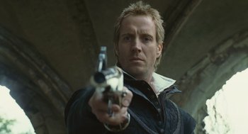Movie still from “Elizabeth: The Golden Age” (2007), directed by Shekhar Kapur – A man holding a gun while standing in front of a building; Close Up shot, Low angle
