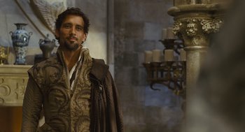Movie still from “Elizabeth: The Golden Age” (2007), directed by Shekhar Kapur – A man standing next to a pillar in a room; Medium shot, Over the shoulder angle