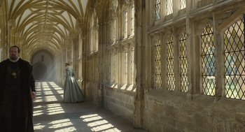 Movie still from “Elizabeth: The Golden Age” (2007), directed by Shekhar Kapur – A woman in a long dress is standing by a window; Extreme Wide shot, Low angle