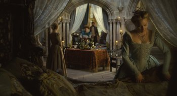Movie still from “Elizabeth: The Golden Age” (2007), directed by Shekhar Kapur – A group of people standing around a table with food on it; Wide shot, High angle