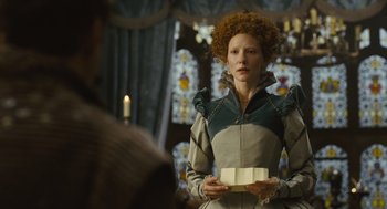 Movie still from “Elizabeth: The Golden Age” (2007), directed by Shekhar Kapur – A woman with a book in her hands in front of a window; Medium shot, Over the shoulder angle