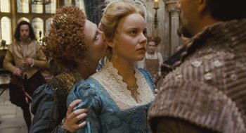 Movie still from “Elizabeth: The Golden Age” (2007), directed by Shekhar Kapur – A woman in a blue dress is being kissed on the cheek by another woman; Close Up shot, Over the shoulder angle