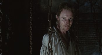 Movie still from “Elizabeth: The Golden Age” (2007), directed by Shekhar Kapur – A man standing in a room with chains hanging from the ceiling; Close Up shot, Low angle