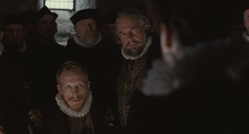 Movie still from “Elizabeth: The Golden Age” (2007), directed by Shekhar Kapur – A group of men in medieval clothing looking at each other; Medium shot, Over the shoulder angle