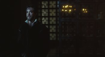 Movie still from “Elizabeth: The Golden Age” (2007), directed by Shekhar Kapur – A man standing in a dark room with lights in the background; Medium shot, Over the shoulder angle