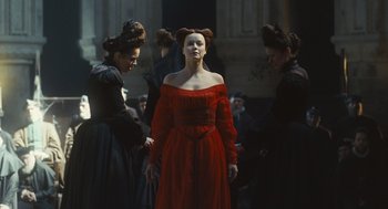 Movie still from “Elizabeth: The Golden Age” (2007), directed by Shekhar Kapur – A woman in a red dress standing in front of other women; Medium shot, Low angle