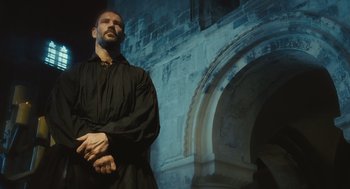 Movie still from “Elizabeth: The Golden Age” (2007), directed by Shekhar Kapur – A man in a black robe standing in front of an arch; Medium shot, Low angle