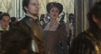 Movie still from “Elizabeth: The Golden Age” (2007), directed by Shekhar Kapur – A woman in a brown dress standing next to a man in a brown suit; Medium shot, Over the shoulder angle